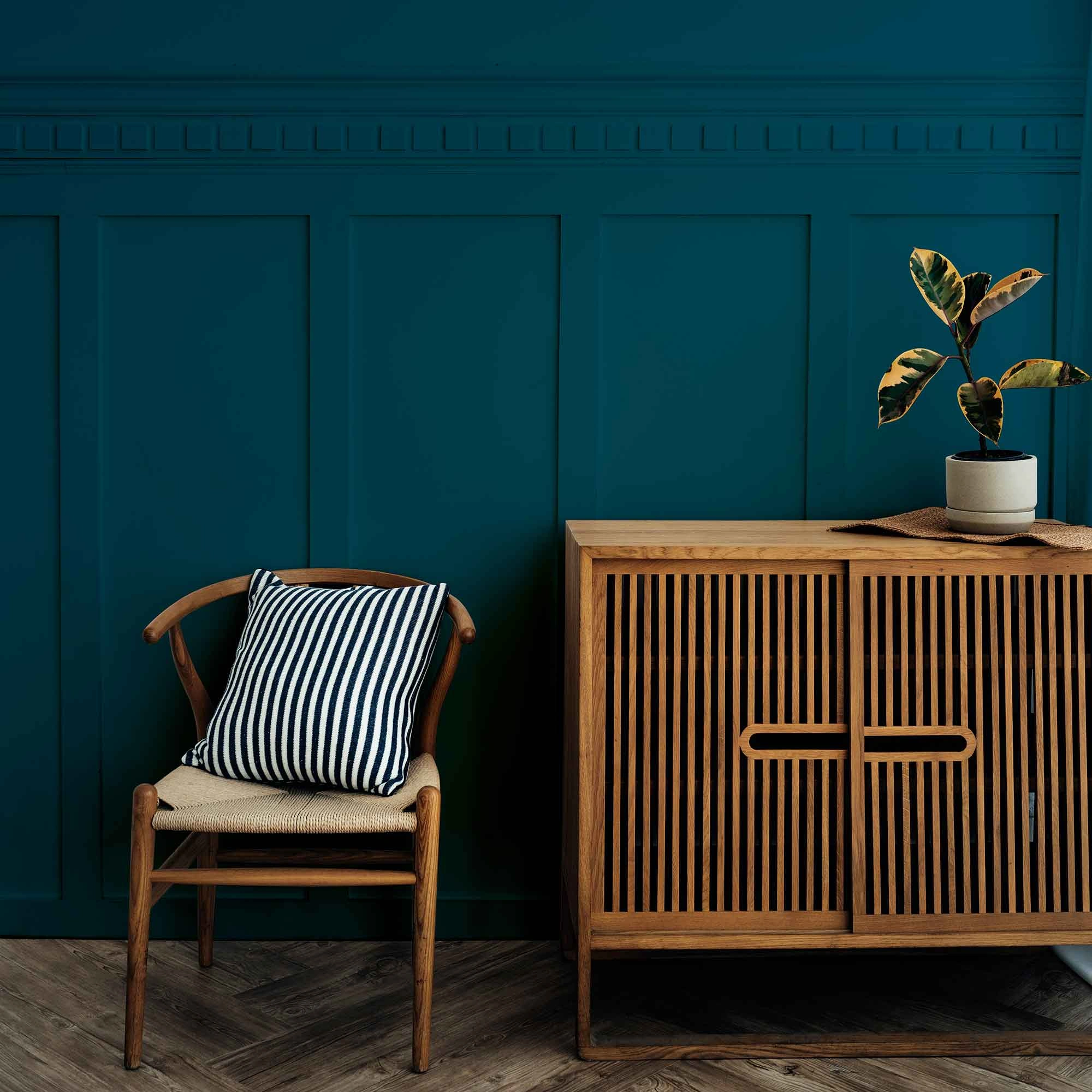 A wooden cabinet and chair set against a blue wall, showcasing stylish furniture 3D rendering for e-commerce interiors